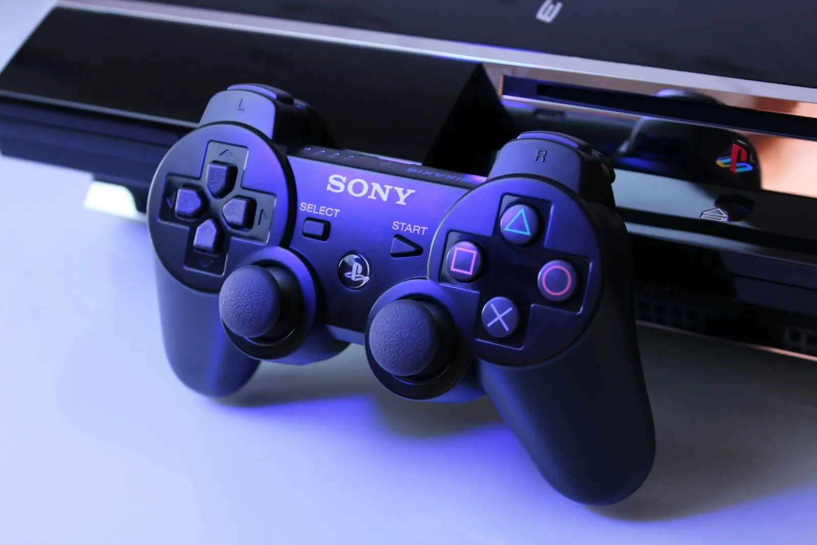 A gamepad in front of a games console on a light background